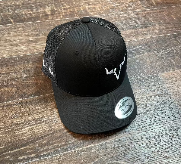 A black snapback cap with a white embroidered Prairie Yak Farms logo on the front.